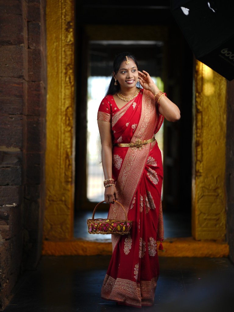 Sai walking in a red saree holding a basket of flowers