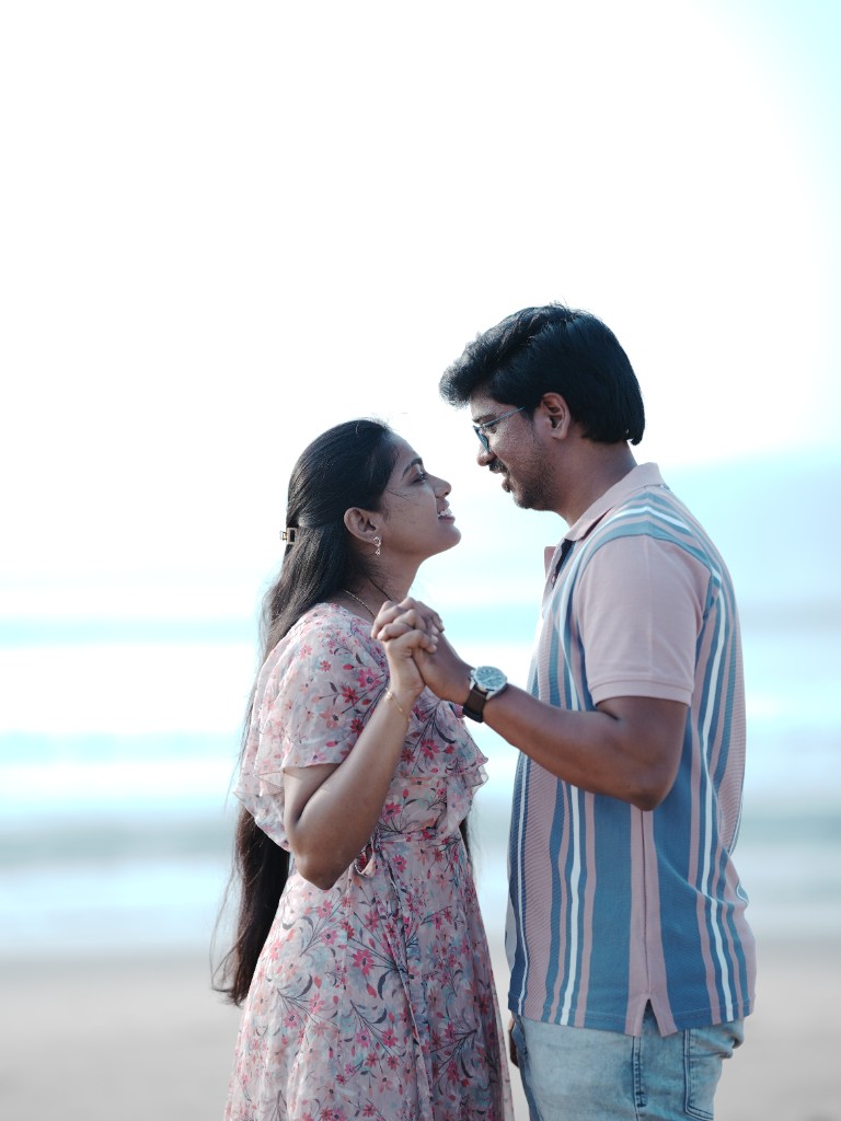 Srinu and Sai holding hands and smiling by the sea