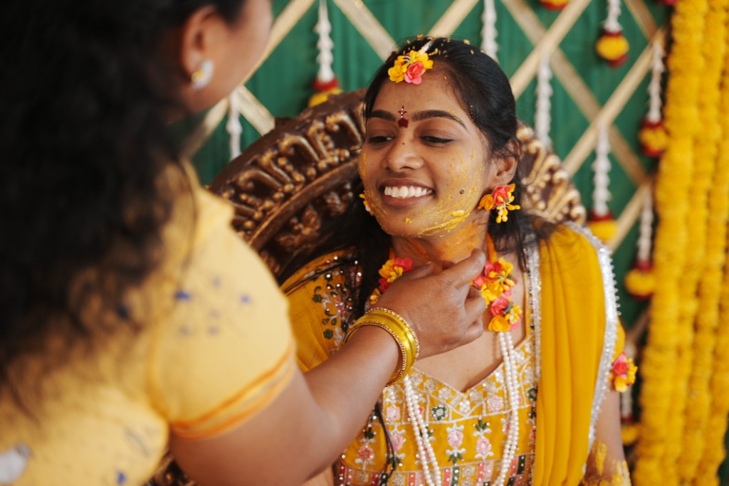 Haldi being applied to the bride's face with a joyful expression